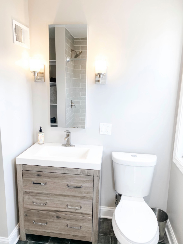Photo of a small traditional bathroom in Chicago with flat-panel cabinets, distressed cabinets, an alcove bath, a shower/bath combination, a two-piece toilet, grey tiles, porcelain tiles, grey walls, porcelain flooring, an integrated sink, blue floors, a shower curtain, white worktops, a single sink and a freestanding vanity unit.