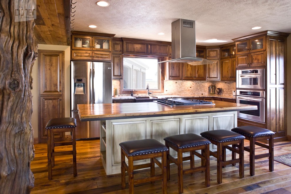 Inspiration for a mid-sized transitional l-shaped medium tone wood floor and brown floor eat-in kitchen remodel with raised-panel cabinets, medium tone wood cabinets, wood countertops, stainless steel appliances, beige walls, an island, a farmhouse sink, multicolored backsplash and mosaic tile backsplash