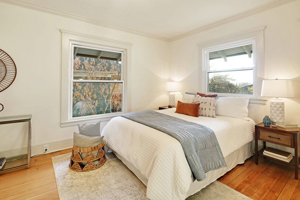This is an example of a large arts and crafts master bedroom in Seattle with white walls, medium hardwood floors and brown floor.