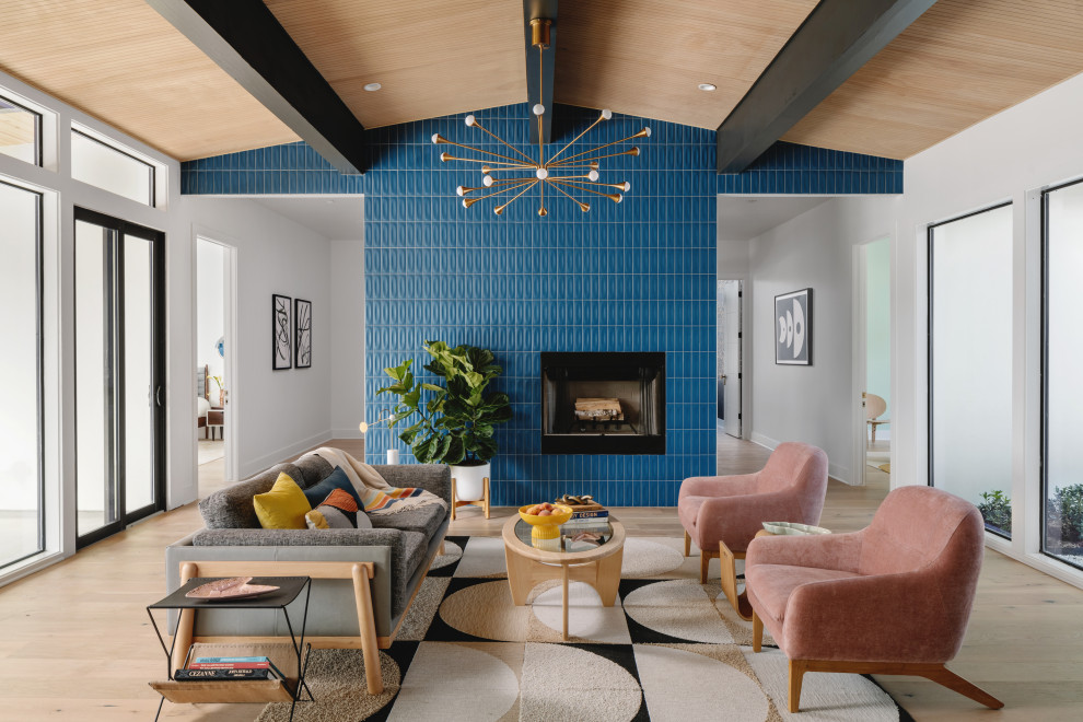 Diseño de salón abierto retro grande con paredes azules, suelo de madera en tonos medios, todas las chimeneas, marco de chimenea de baldosas y/o azulejos y madera