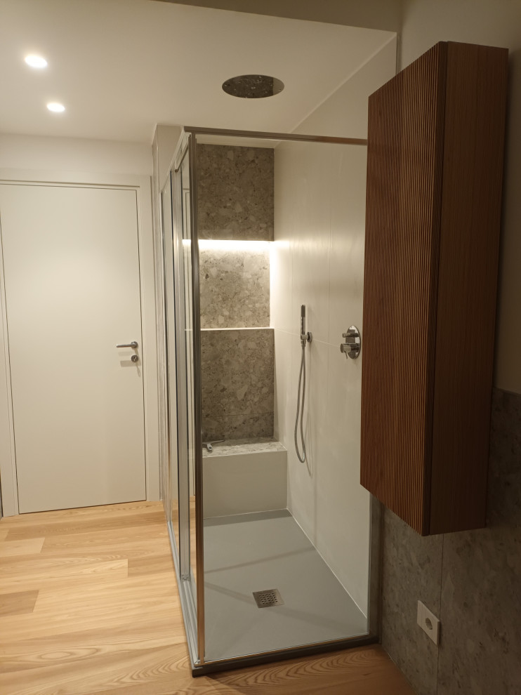 This is an example of a medium sized contemporary shower room bathroom in Milan with light wood cabinets, a built-in shower, a two-piece toilet, grey tiles, porcelain tiles, white walls, medium hardwood flooring, a vessel sink, engineered stone worktops, a sliding door, white worktops, a single sink, a floating vanity unit and a drop ceiling.