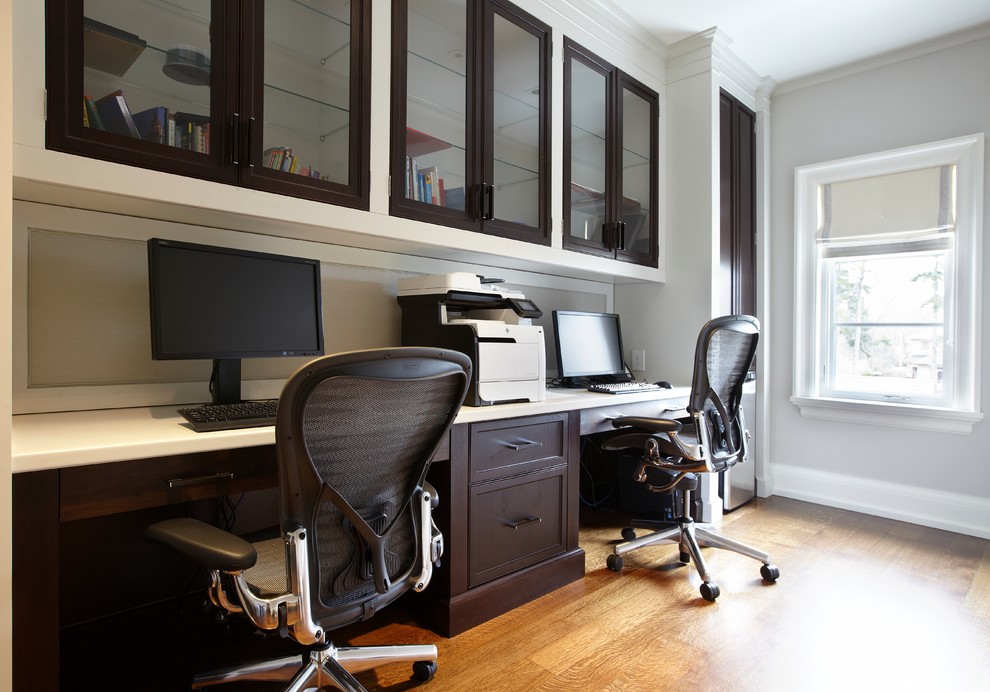 Photo of a large transitional study room in Toronto with a built-in desk, grey walls, medium hardwood floors, no fireplace and brown floor.