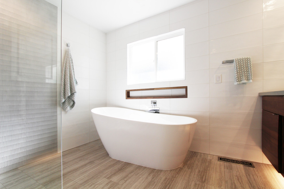 Large transitional master white tile and ceramic tile porcelain tile, gray floor and double-sink freestanding bathtub photo with flat-panel cabinets, dark wood cabinets, a one-piece toilet, white walls, an undermount sink, quartz countertops, gray countertops, a niche and a floating vanity