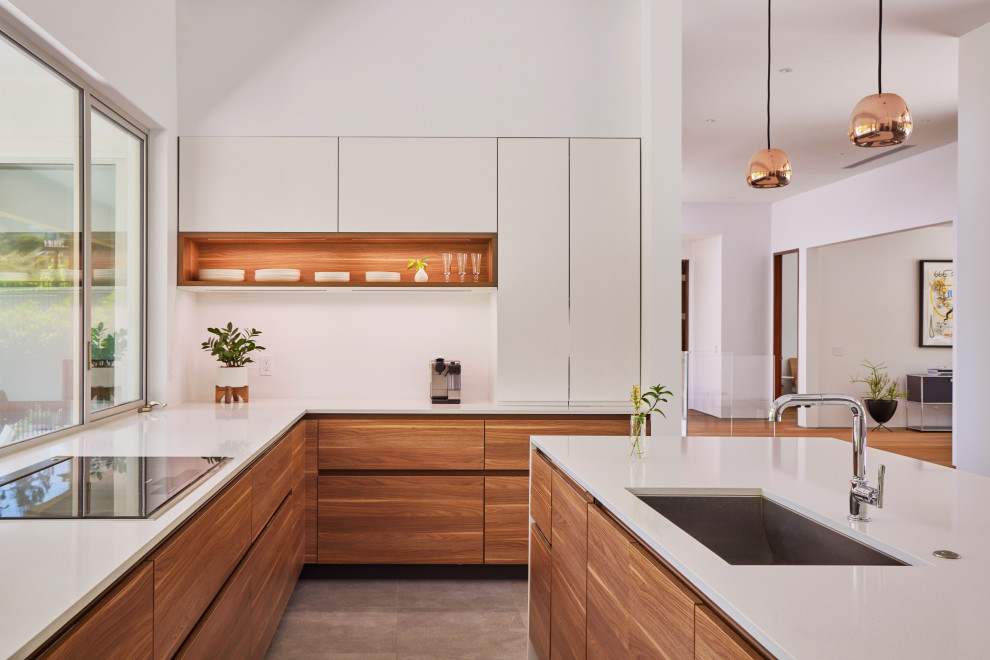 Example of a mid-sized trendy l-shaped porcelain tile and gray floor eat-in kitchen design in Los Angeles with an undermount sink, flat-panel cabinets, medium tone wood cabinets, quartz countertops, white backsplash, quartz backsplash, stainless steel appliances, an island and white countertops