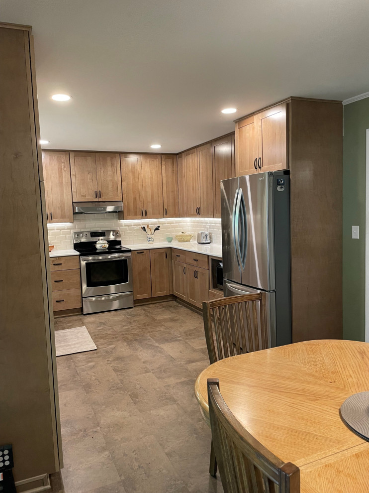This is an example of a mid-sized modern u-shaped eat-in kitchen in Other with medium wood cabinets, quartz benchtops, subway tile splashback, vinyl floors and white benchtop.