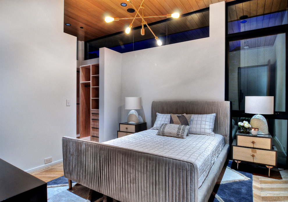 This is an example of a mid-sized contemporary guest bedroom in Orange County with white walls, light hardwood floors and no fireplace.