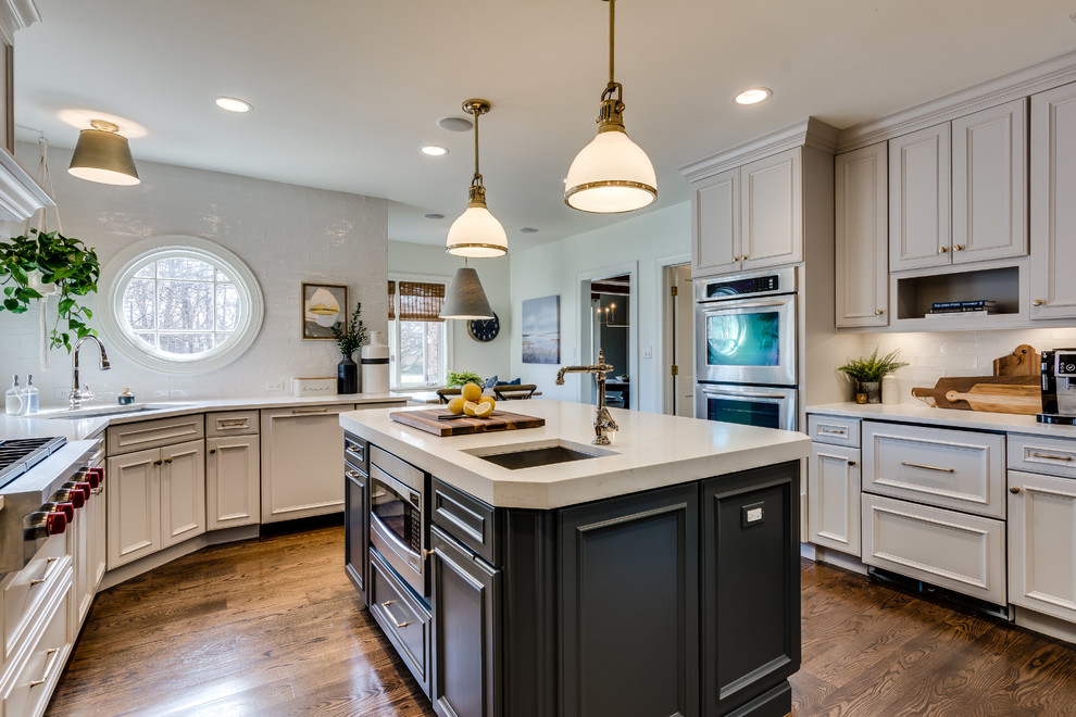 Eat-in kitchen - transitional dark wood floor and brown floor eat-in kitchen idea in Chicago with an undermount sink, recessed-panel cabinets, beige cabinets, white backsplash, glass tile backsplash, stainless steel appliances, an island and beige countertops