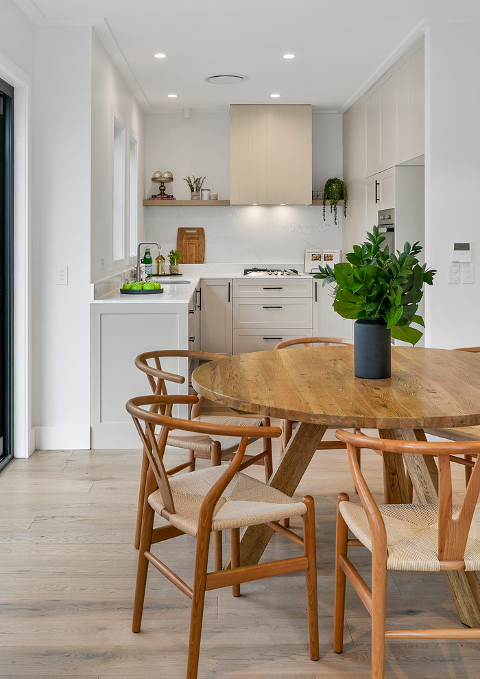 Inspiration for a small transitional l-shaped open plan kitchen in Sydney with a double-bowl sink, shaker cabinets, marble benchtops, marble splashback, stainless steel appliances, light hardwood floors, with island, white benchtop and beige cabinets.