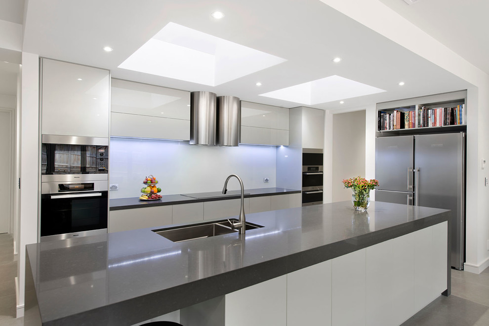 Design ideas for a modern galley kitchen pantry in Melbourne with an undermount sink, flat-panel cabinets, grey cabinets, quartz benchtops, metallic splashback, glass sheet splashback, stainless steel appliances, porcelain floors and with island.