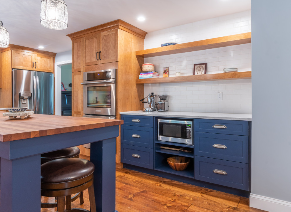 Enclosed kitchen - large transitional medium tone wood floor enclosed kitchen idea in Boston with a farmhouse sink, shaker cabinets, light wood cabinets, quartz countertops, white backsplash, subway tile backsplash, stainless steel appliances, an island and white countertops