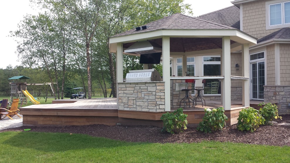 Expansive backyard deck in Milwaukee with an outdoor kitchen and a pergola.