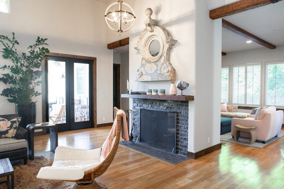 This is an example of a large eclectic open concept living room in Portland with white walls, medium hardwood floors, a two-sided fireplace, a stone fireplace surround, brown floor and exposed beam.
