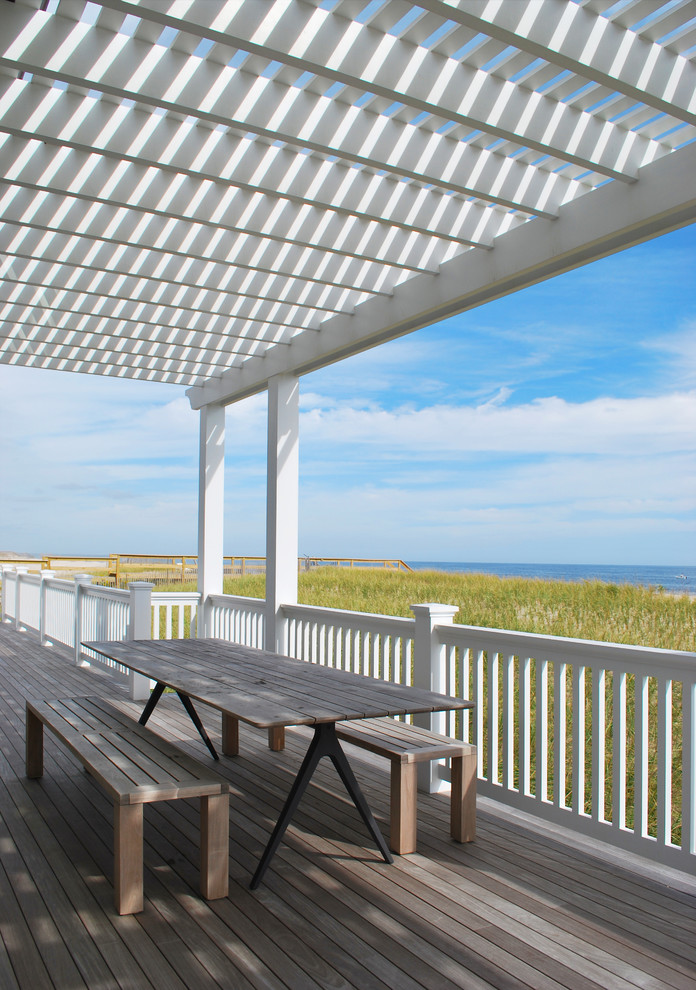 This is an example of a beach style backyard verandah in New York with decking and a pergola.