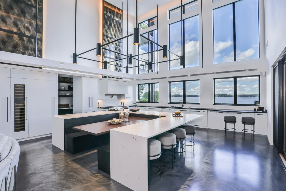 Contemporary l-shaped open plan kitchen in Other with flat-panel cabinets, white cabinets, solid surface benchtops, stainless steel appliances, concrete floors, with island, grey floor, white benchtop and recessed.