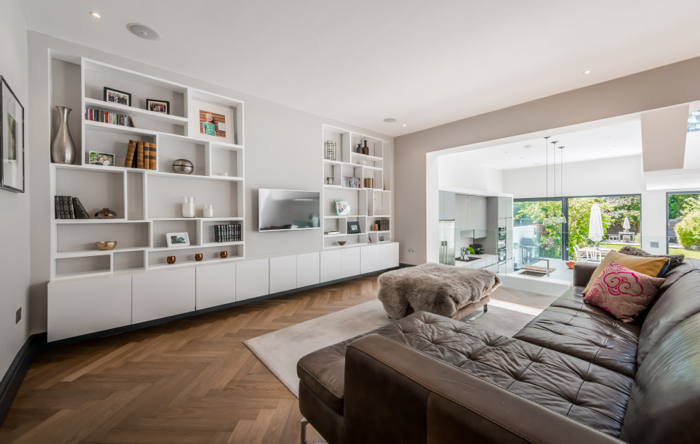 Inspiration for a contemporary living room in London with grey walls, dark hardwood floors, a wall-mounted tv and brown floor.