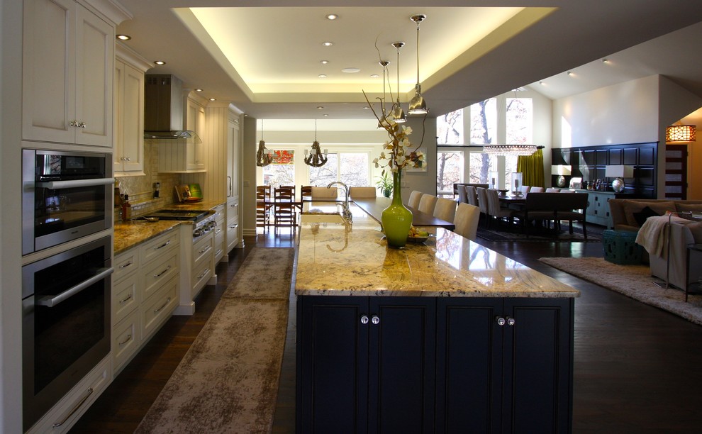 Large transitional single-wall dark wood floor and brown floor open concept kitchen photo in Kansas City with a farmhouse sink, recessed-panel cabinets, white cabinets, granite countertops, beige backsplash, paneled appliances, an island and multicolored countertops