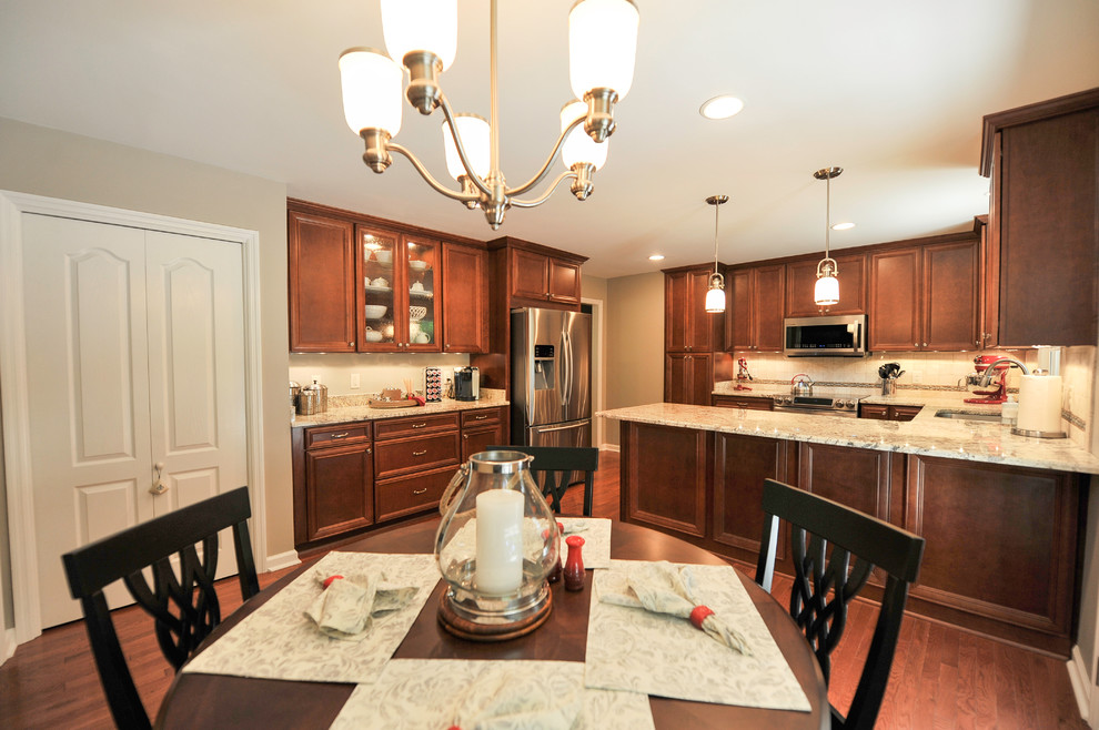 Eat-in kitchen - mid-sized transitional u-shaped medium tone wood floor eat-in kitchen idea in Birmingham with a double-bowl sink, flat-panel cabinets, medium tone wood cabinets, granite countertops, beige backsplash, stone tile backsplash, stainless steel appliances and a peninsula