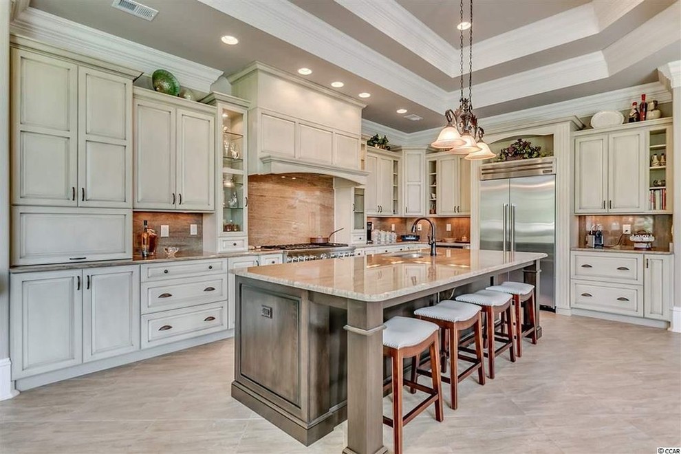 Inspiration for a large mediterranean kitchen in Charleston with a double-bowl sink, raised-panel cabinets, beige cabinets, granite benchtops, porcelain floors, with island and beige floor.