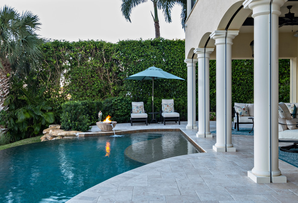 Design ideas for a large mediterranean backyard custom-shaped infinity pool in Miami with a water feature and concrete pavers.