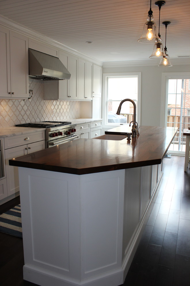 Eat-in kitchen - large transitional galley dark wood floor eat-in kitchen idea in Baltimore with a farmhouse sink, shaker cabinets, white cabinets, wood countertops, white backsplash, ceramic backsplash, stainless steel appliances and an island