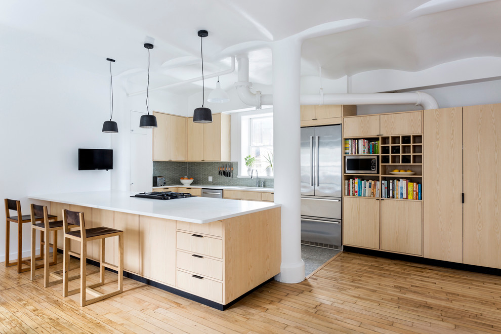 Photo of a contemporary kitchen in New York with an undermount sink, flat-panel cabinets, light wood cabinets, stainless steel appliances, light hardwood floors and a peninsula.