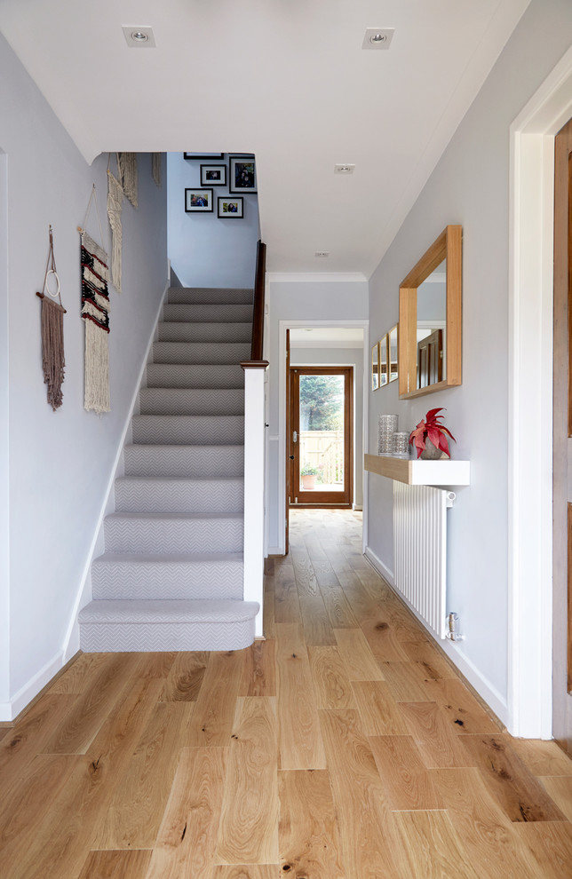 This is an example of a transitional carpeted staircase in London with wood railing.