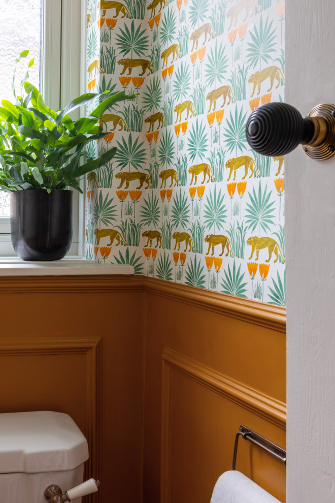 Kleine Klassische Gästetoilette mit oranger Wandfarbe, schwarzem Boden und Wandpaneelen in London