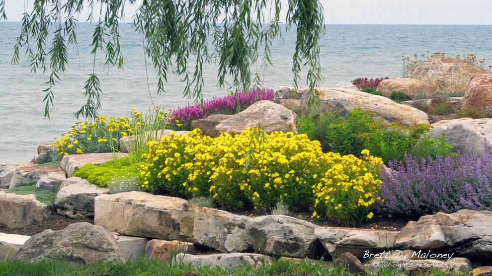 Large beach style sloped full sun xeriscape in Other with a retaining wall for summer.