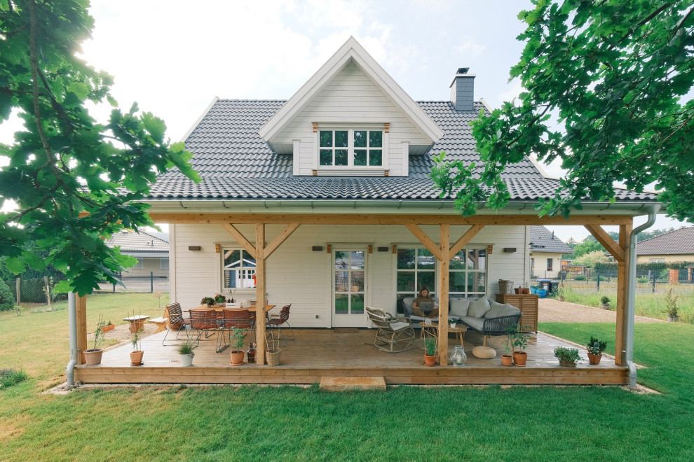 Imagen de fachada de casa blanca y negra escandinava de tamaño medio de una planta con revestimiento de madera, tejado a dos aguas, tejado de teja de barro y tablilla