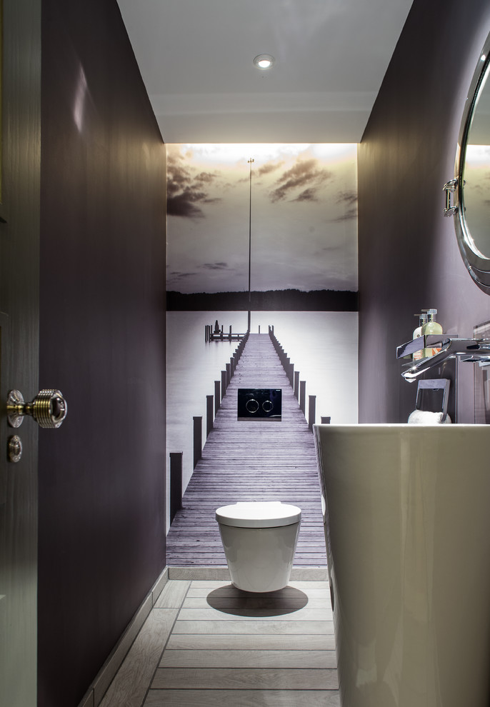 Photo of a mid-sized contemporary powder room in London with a pedestal sink, a wall-mount toilet and purple walls.