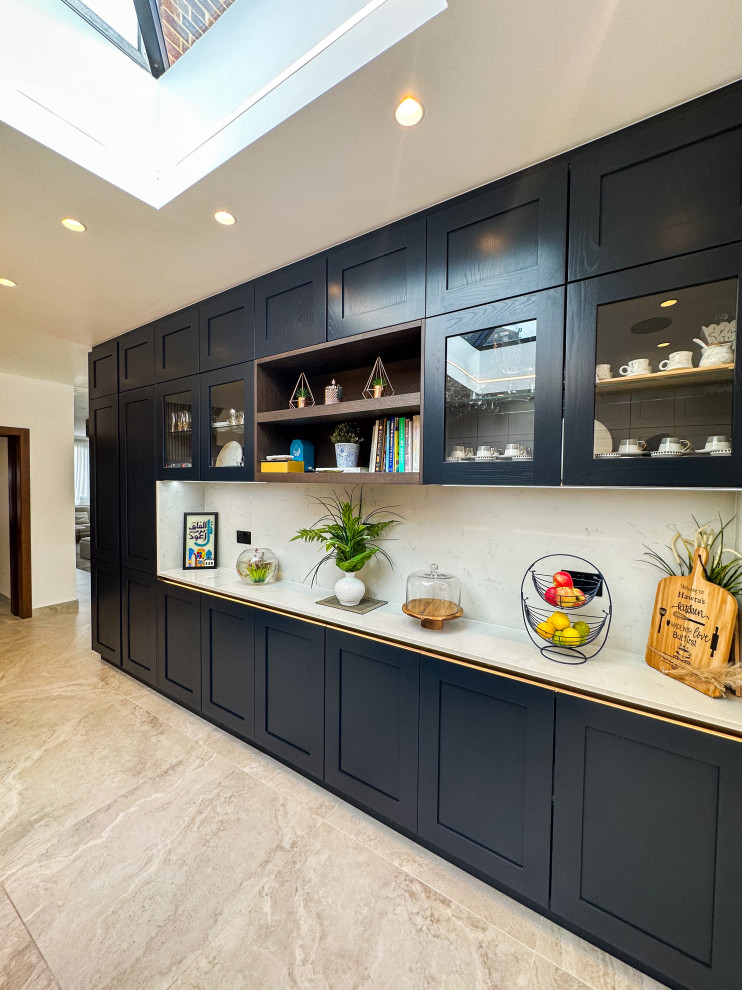 Design ideas for a large traditional l-shaped kitchen/diner in London with a built-in sink, shaker cabinets, blue cabinets, quartz worktops, white splashback, engineered quartz splashback, integrated appliances, porcelain flooring, an island, beige floors, white worktops and feature lighting.
