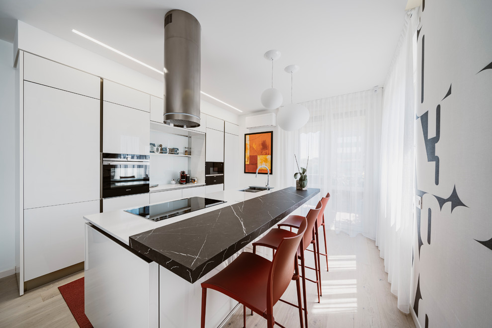 Photo of a large modern galley open plan kitchen in Milan with a double-bowl sink, glass-front cabinets, white cabinets, solid surface benchtops, white splashback, glass sheet splashback, stainless steel appliances, light hardwood floors, with island, beige floor and multi-coloured benchtop.