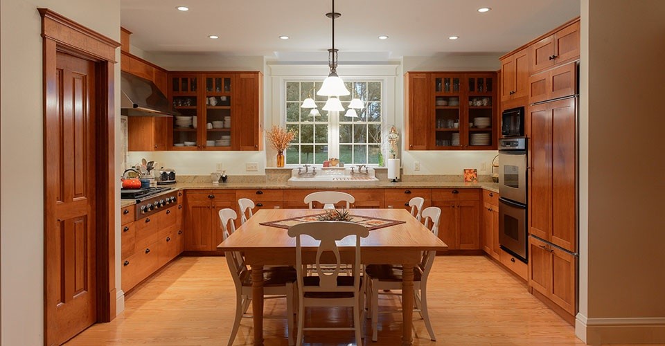 Large arts and crafts u-shaped light wood floor and brown floor eat-in kitchen photo with medium tone wood cabinets, granite countertops, stainless steel appliances, shaker cabinets, an island and a drop-in sink
