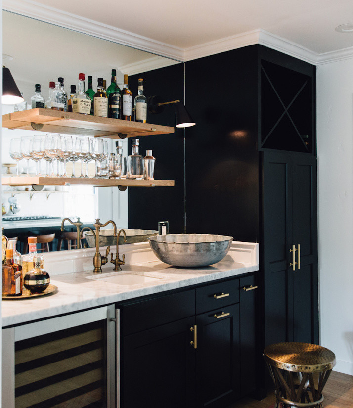 This is an example of a mid-sized transitional single-wall wet bar in San Francisco with an undermount sink, recessed-panel cabinets, black cabinets, quartzite benchtops, mirror splashback and light hardwood floors.