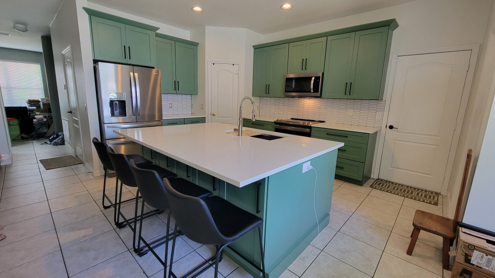 Example of a mid-sized transitional l-shaped eat-in kitchen design in Orlando with shaker cabinets, green cabinets, quartz countertops, white backsplash, subway tile backsplash, an island and white countertops