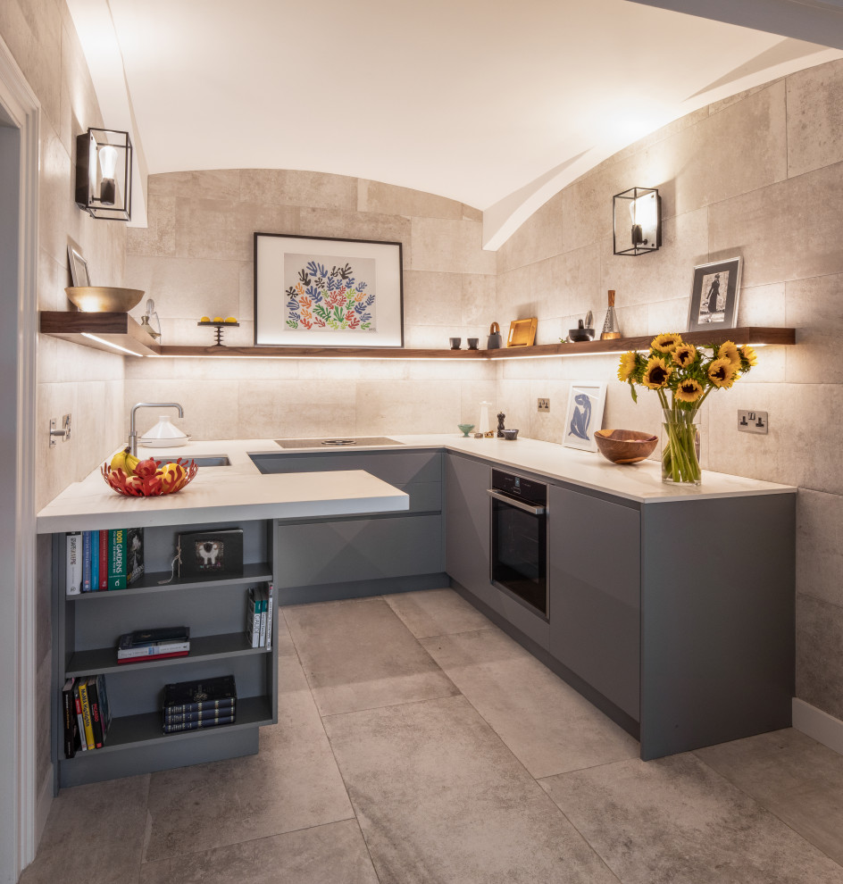 Photo of a mid-sized contemporary u-shaped separate kitchen in London with an integrated sink, flat-panel cabinets, grey cabinets, quartz benchtops, grey splashback, white benchtop, porcelain splashback, panelled appliances, porcelain floors, a peninsula and grey floor.
