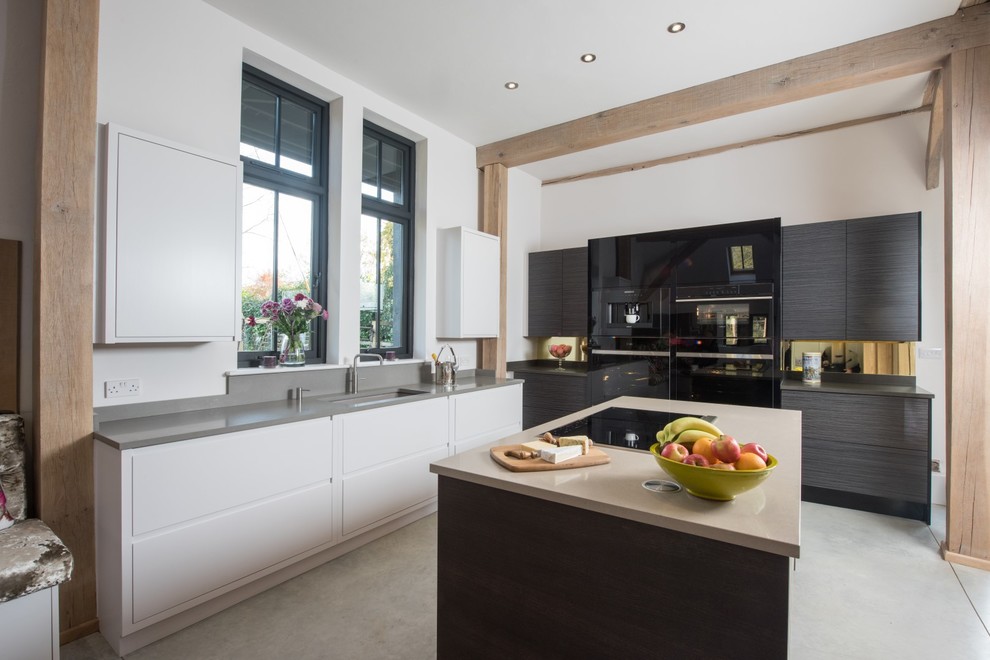 Design ideas for an expansive contemporary l-shaped open plan kitchen in Essex with flat-panel cabinets, black appliances, multiple islands, beige benchtop, an undermount sink, concrete floors and grey floor.