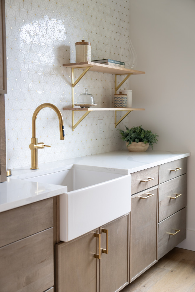 Inspiration for a transitional medium tone wood floor kitchen remodel with a farmhouse sink, quartzite countertops, marble backsplash and an island