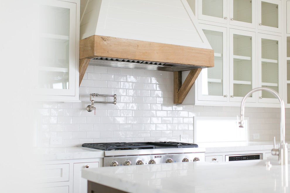 Open concept kitchen - large transitional u-shaped light wood floor and brown floor open concept kitchen idea in Orange County with a farmhouse sink, shaker cabinets, white cabinets, marble countertops, white backsplash, subway tile backsplash, stainless steel appliances and an island