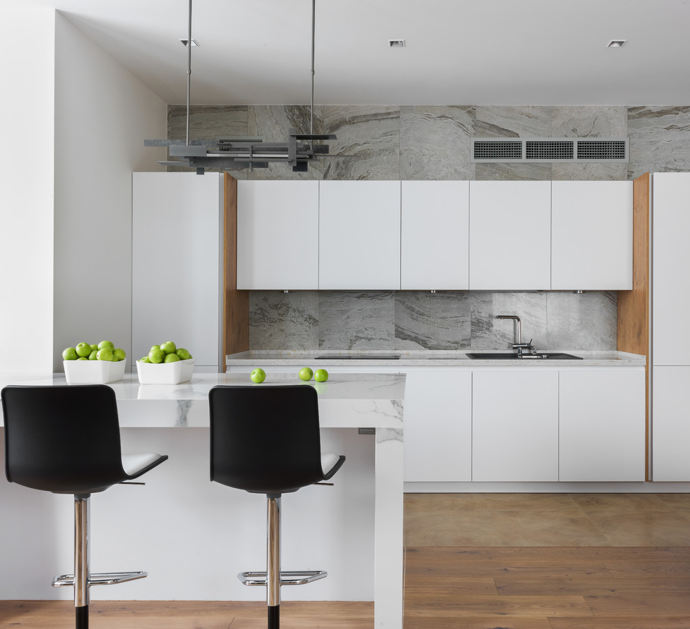 Contemporary single-wall open plan kitchen in Moscow with a drop-in sink, flat-panel cabinets, white cabinets, grey splashback, brown floor and a peninsula.