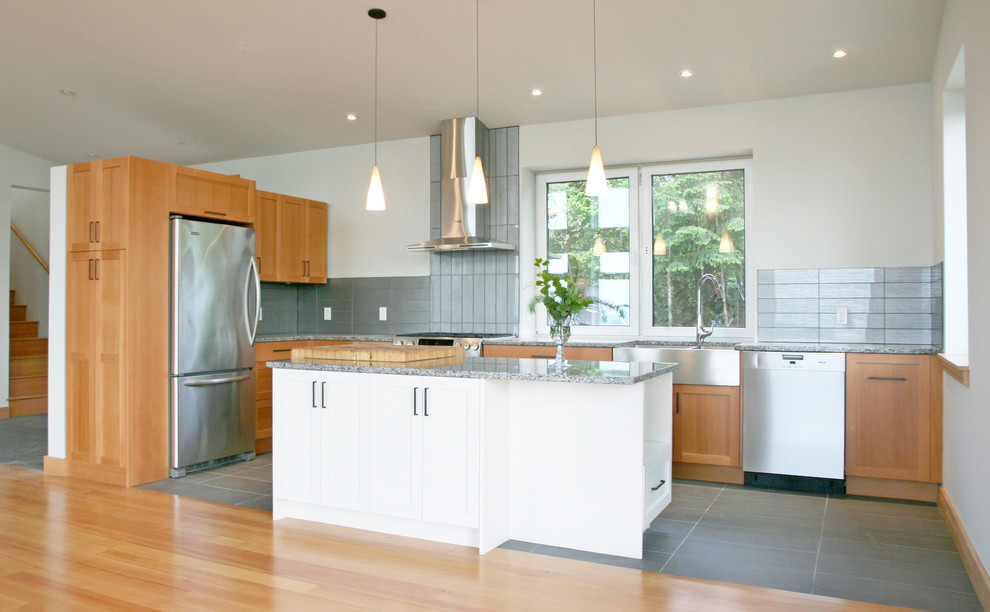 Design ideas for a mid-sized contemporary l-shaped eat-in kitchen in Vancouver with a farmhouse sink, shaker cabinets, medium wood cabinets, granite benchtops, grey splashback, glass tile splashback, stainless steel appliances, cement tiles, with island and grey floor.