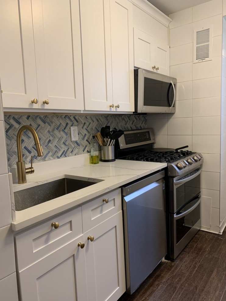 Photo of a transitional kitchen in New York with shaker cabinets, white cabinets, quartz benchtops, blue splashback, mosaic tile splashback and white benchtop.