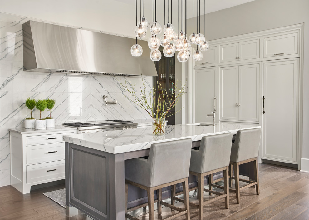 This is an example of a large transitional eat-in kitchen in Chicago with a single-bowl sink, shaker cabinets, white cabinets, quartzite benchtops, grey splashback, stone slab splashback, stainless steel appliances, dark hardwood floors and with island.