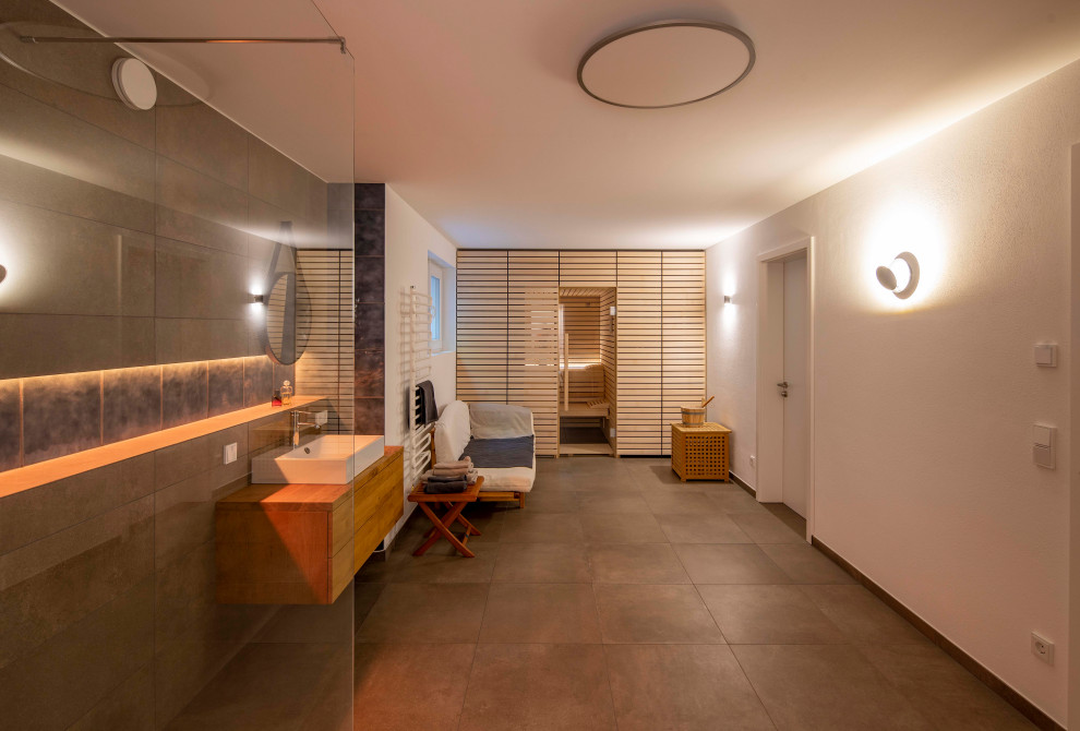 Moderne Sauna mit hellbraunen Holzschränken, Einbaubadewanne, bodengleicher Dusche, grauen Fliesen, Aufsatzwaschbecken, grauem Boden, offener Dusche, brauner Waschtischplatte, Doppelwaschbecken und Holzdecke in München