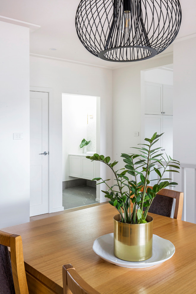 Photo of a mid-sized contemporary kitchen/dining combo in Sydney with white walls, painted wood floors and black floor.