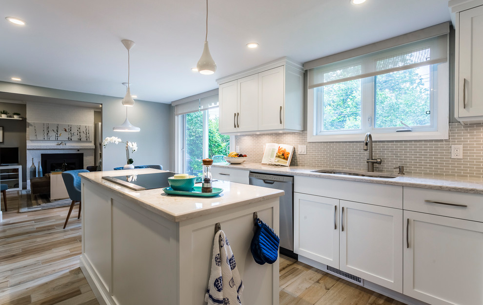 Mid-sized transitional l-shaped porcelain tile and beige floor eat-in kitchen photo with an undermount sink, shaker cabinets, white cabinets, quartz countertops, gray backsplash, mosaic tile backsplash, stainless steel appliances and an island