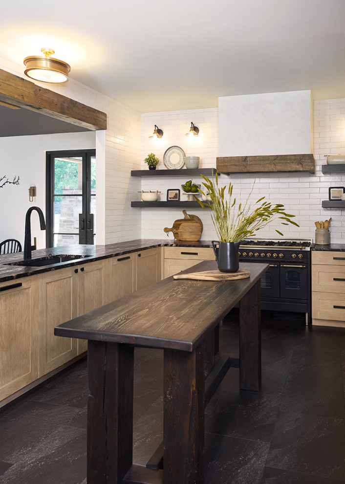 This is an example of a large country u-shaped eat-in kitchen in Grand Rapids with an undermount sink, recessed-panel cabinets, light wood cabinets, granite benchtops, white splashback, subway tile splashback, panelled appliances, with island, black floor and black benchtop.