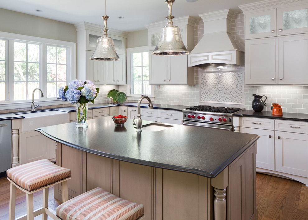 This is an example of a traditional l-shaped kitchen in DC Metro with a farmhouse sink, shaker cabinets, grey cabinets, grey splashback, subway tile splashback, stainless steel appliances, medium hardwood floors and with island.