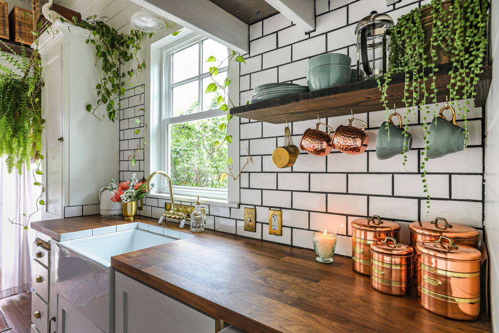 Small country kitchen in Portland with white cabinets, wood benchtops, white splashback, subway tile splashback, dark hardwood floors, no island, brown floor, brown benchtop, a farmhouse sink, shaker cabinets, exposed beam and timber.