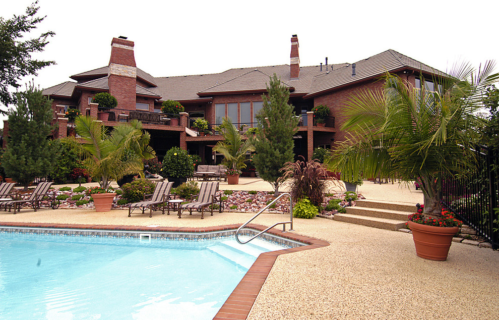 Large transitional backyard stamped concrete and custom-shaped lap pool photo in Omaha